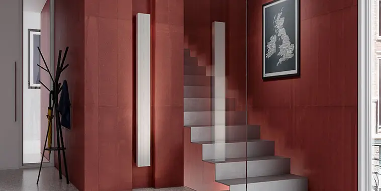 Ein Badezimmer- und Wohnheizkörper von Kermi, Modell Niva T21 in Weiß, hängt an einer roten Wand neben einer Treppe.